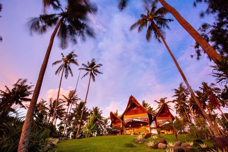 A Bali villa at sunset, framed by coconut palms